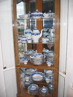 a china cabinet filled with lots of blue and white dishes on top of wooden shelves