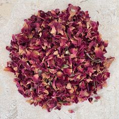 a pile of dried red flowers sitting on top of a white table next to a wall