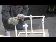 a man in grey shirt and white gloves working with pipes on top of a table