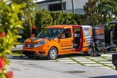 an orange van parked in front of a house with its door open and the driver inside