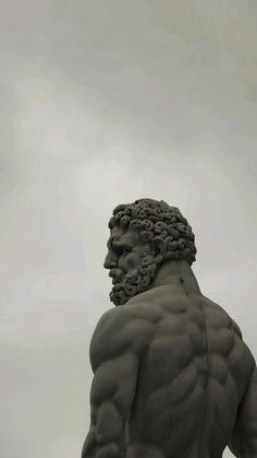 a statue of a man with no shirt on standing in front of a cloudy sky