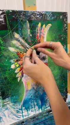 a woman is painting on an easel with her hands