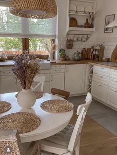 a kitchen with white cabinets and wicker dining room chairs in front of the table