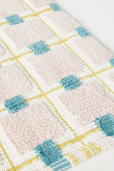 a close up of a rug on the floor with blue, yellow and white squares