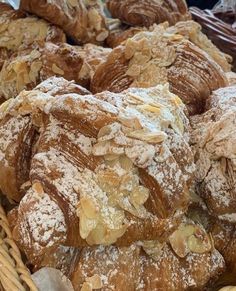 many pastries are piled up in a wicker basket with powdered sugar on top