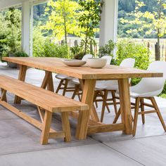 a wooden table with two white chairs and a bowl on it sitting next to a bench