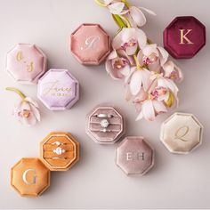 wedding rings, ring boxes and flowers on a white surface with monogrammed letters