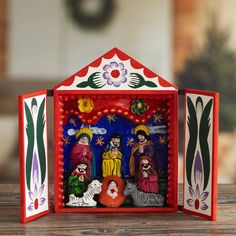 an ornament depicting the birth of jesus in a red box on a wooden table