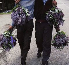 two men are walking down the street with wreaths on their heads and holding flowers