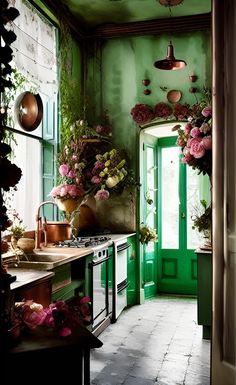 a kitchen with green painted walls and flowers on the counter top, potted plants in front of an open door