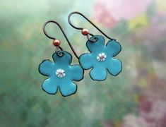 I can make these flowers in most any color. the last two photos show colors I often use. Let me know what you like! These earrings is made from copper sheet that has been cut out, sanded, and hammered into a slightly domed shape. The copper shape is carefully cleaned and prepared in order to accept the enamel. I apply multiple layers of enamel, which is finely powdered glass, first to the back (usually in black) and then the front of the piece. Each application must be fired with a mixed fuel to Handmade Copper Flower Earrings, Handmade Turquoise Flower Earrings, Copper Sheets, Orange Cats, Simple Flower, Tree Pendant, Simple Flowers, Enamel Earrings, Enamel Jewelry