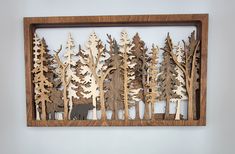 a wooden cutout of trees with an animal in the woods behind it on a wall