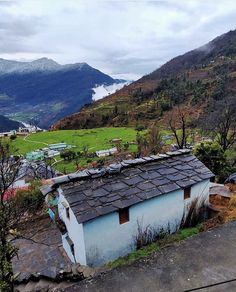 a small blue building sitting on top of a lush green hillside next to a valley