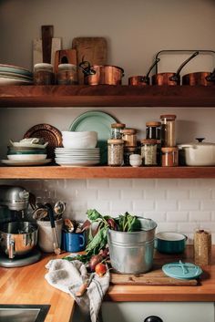 the shelves in the kitchen are full of pots and pans, with dishes on them