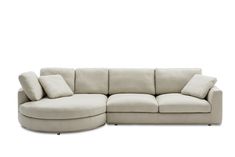 a white sectional couch with pillows on the top and bottom corner, in front of a white background