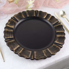 a black plate sitting on top of a table next to utensils and flowers