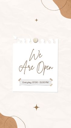 we are open sign on white paper with gold stars and confetti around it