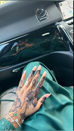 a woman's hand with tattoos on it sitting in a car