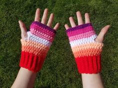 two hands wearing colorful knitted gloves on top of grass