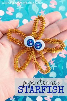 a hand holding a small gold starfish brooch with eyes on it's back