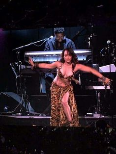 a woman in a leopard print dress on stage with her arms outstretched and legs spread out