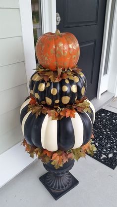 three pumpkins are stacked on top of each other in front of a black door