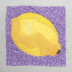 a yellow piece of fabric is on top of a purple and white quilted surface