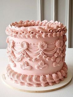 a pink frosted cake sitting on top of a white table