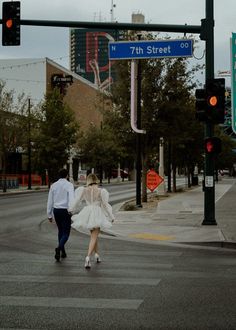 a man and woman are walking across the street in their wedding attire, holding hands