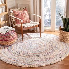 a living room with a chair, rug and potted plant on the floor in front of a window