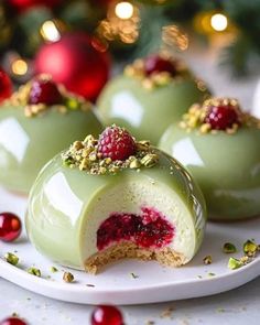 three desserts with raspberry filling on a white plate next to christmas decorations