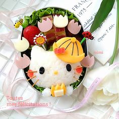 a hello kitty sushi plate with rice and vegetables on it, including strawberries