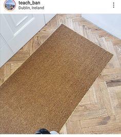 a person standing on the floor next to a brown door mat that has been placed in front of a white door