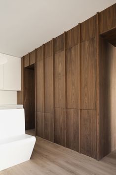 an empty room with wood paneling and white cabinets on the wall, along with wooden flooring