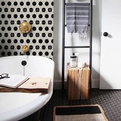 a white bath tub sitting next to a black and white wall