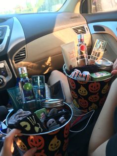 two buckets filled with halloween treats sitting in the front seat of a car,