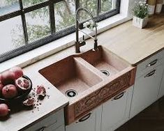 a kitchen sink sitting next to a window with fruit on the counter top in front of it