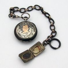 "Antique open face pocket watch, having Swiss movement and 800 silver case with chain and locket charm, decorated with Niello black enamel. Case features gilt depiction of Hermes profile on the back. Locket has two compartments and gilt shield on the front side. c. 1890. Watch runs. This amazing watch is 1 5/8\" in diameter, the chain is 9 3/4\" long. The locket measures 15/16\" long x 3/4\" wide. Total weight is 91.1 grams. EA678." Timeless Engraved Locket Necklace For Formal Occasions, Victorian Medallion Pocket Watch For Formal Occasions, Timeless Medallion Locket Necklace For Formal Occasions, Antique Gold Pocket Watch With Locket For Formal Occasions, Silver Pocket Watch With Locket For Formal Occasions, Formal Medallion Pocket Watch With Locket, Medallion Shaped Pocket Watch With Chronometer As Gift, Silver Locket Pocket Watch For Formal Occasions, Antique Compact Pocket Watch As Gift