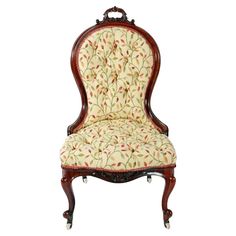 an antique chair with floral upholstered fabric on the back and arms, sitting in front of a white background