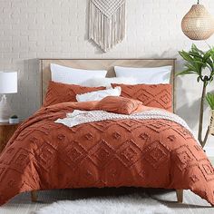 a bed with an orange comforter and pillows