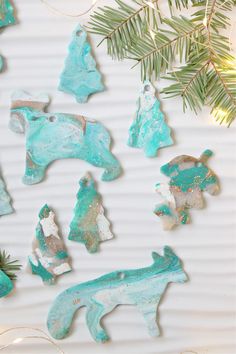 christmas ornaments made out of clay sitting on top of a white surface next to a pine tree