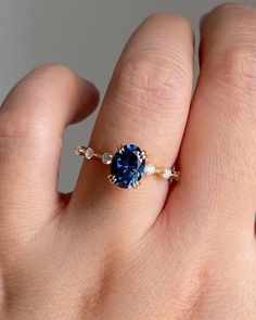 a woman's hand with a blue ring on top of her finger and diamond band around it