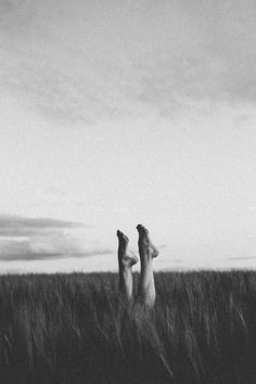 two people standing in the middle of a field with their feet up and arms out