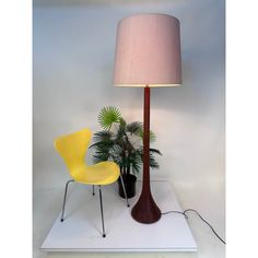 a lamp that is on top of a table next to a chair and potted plant