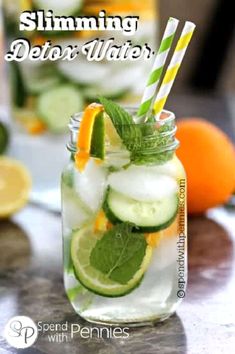 a mason jar filled with cucumber, lemon and mint water next to sliced oranges