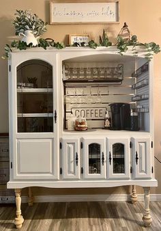 a white china cabinet sitting on top of a hard wood floor next to a wall