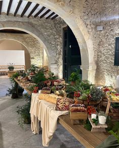 a table with many different types of food on it in an indoor area that looks like a stone building