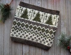 a knitted christmas stocking sitting on top of a wooden table next to pine cones