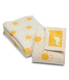 the yellow and white blanket is folded on top of each other, with an image of sun