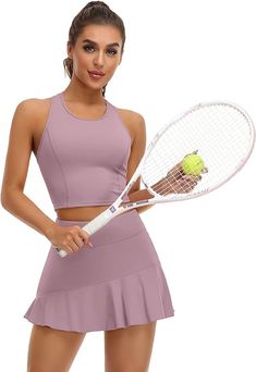 a woman holding a tennis racquet and ball in one hand while wearing a skirt